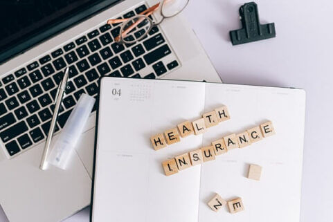 health insurance spelled out on top of diary and computer