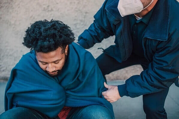 Man getting care from paramedic on sidewalk after being attacked by a dog
