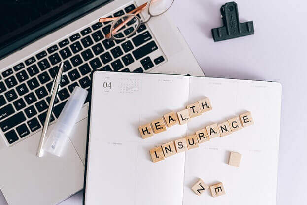 health insurance spelled out on top of diary and computer