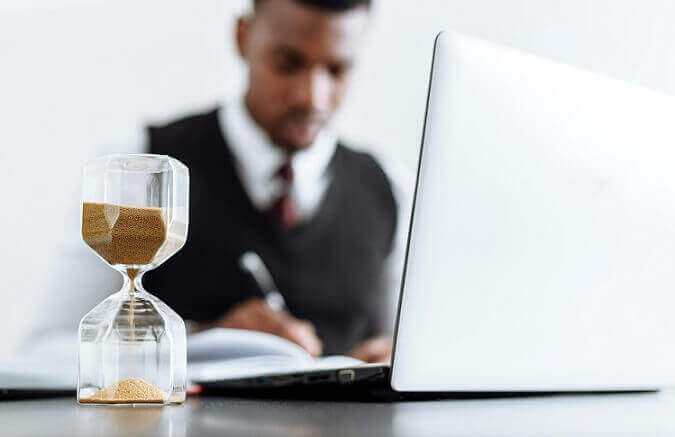 statute of limitations on dog bites shown with hourglass in front of man sitting at desk writing in front of computer